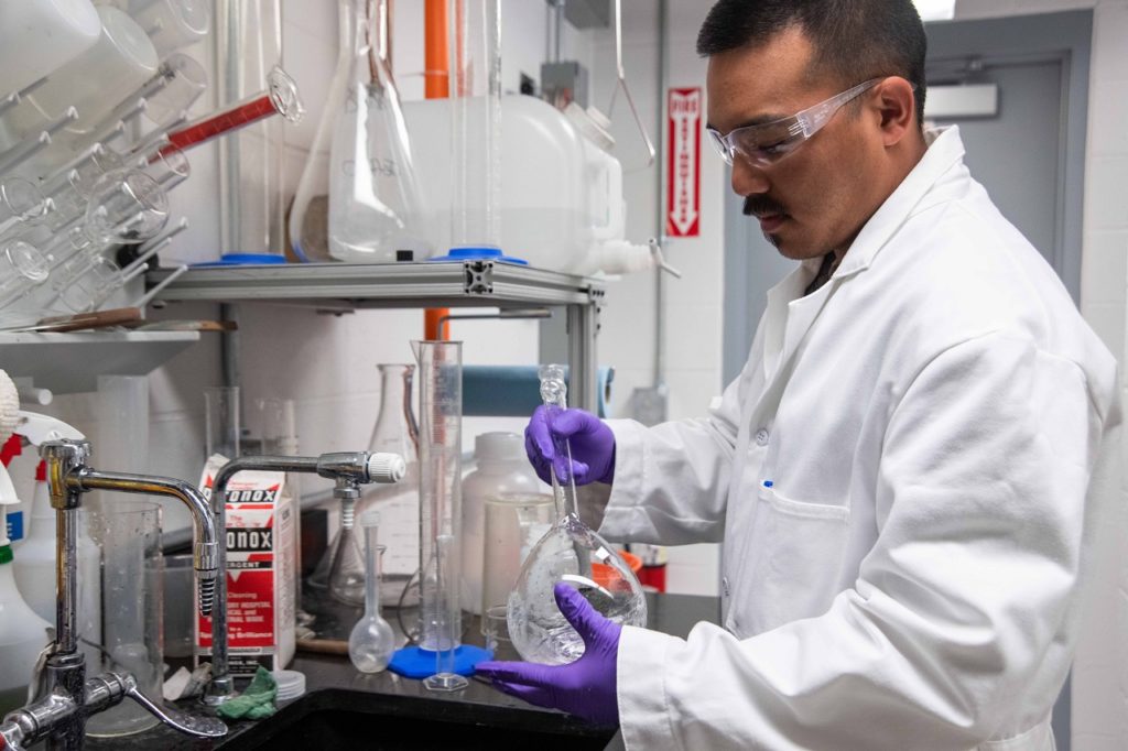 a researcher in a small lab using a  cannabis tool that looks like a florence flask