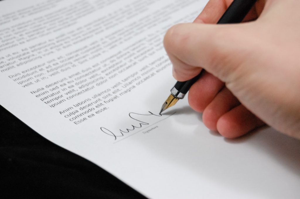 a hand signing a document, representing licenses for cannabis cultivation in Africa