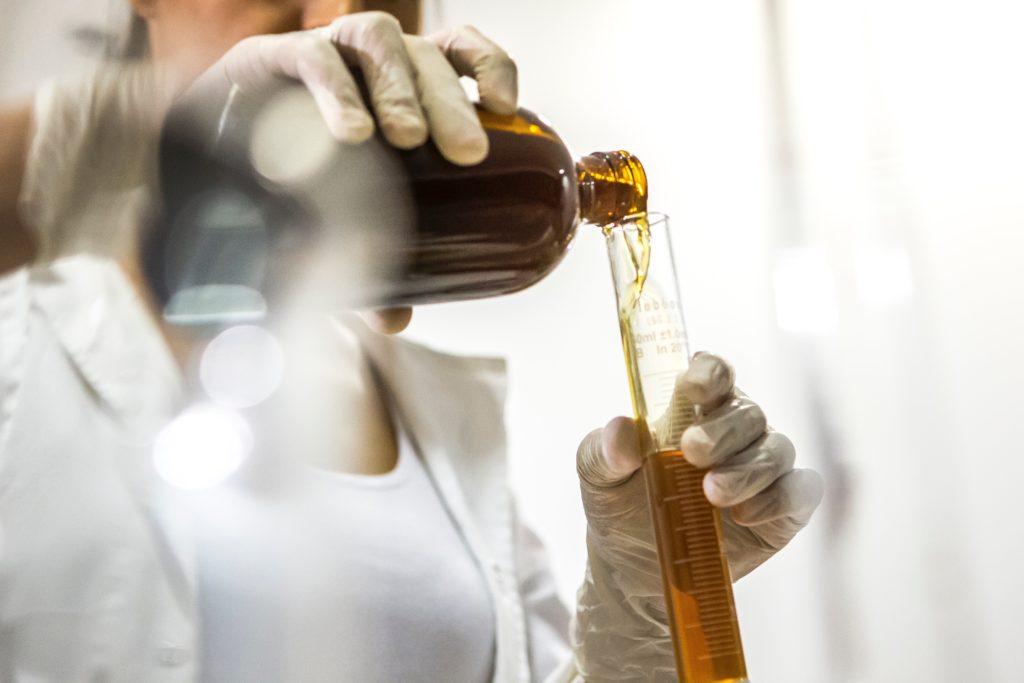 Woman holding bottle and beaker representing the Big Pharma cannabis industry